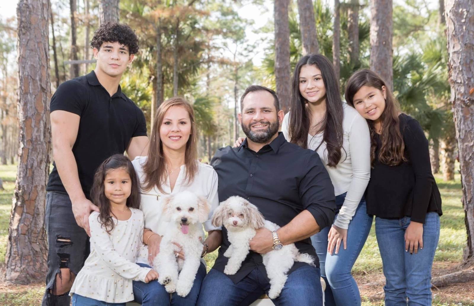 Jorge and Alejandra Garrido with their family and dogs in a pine grove